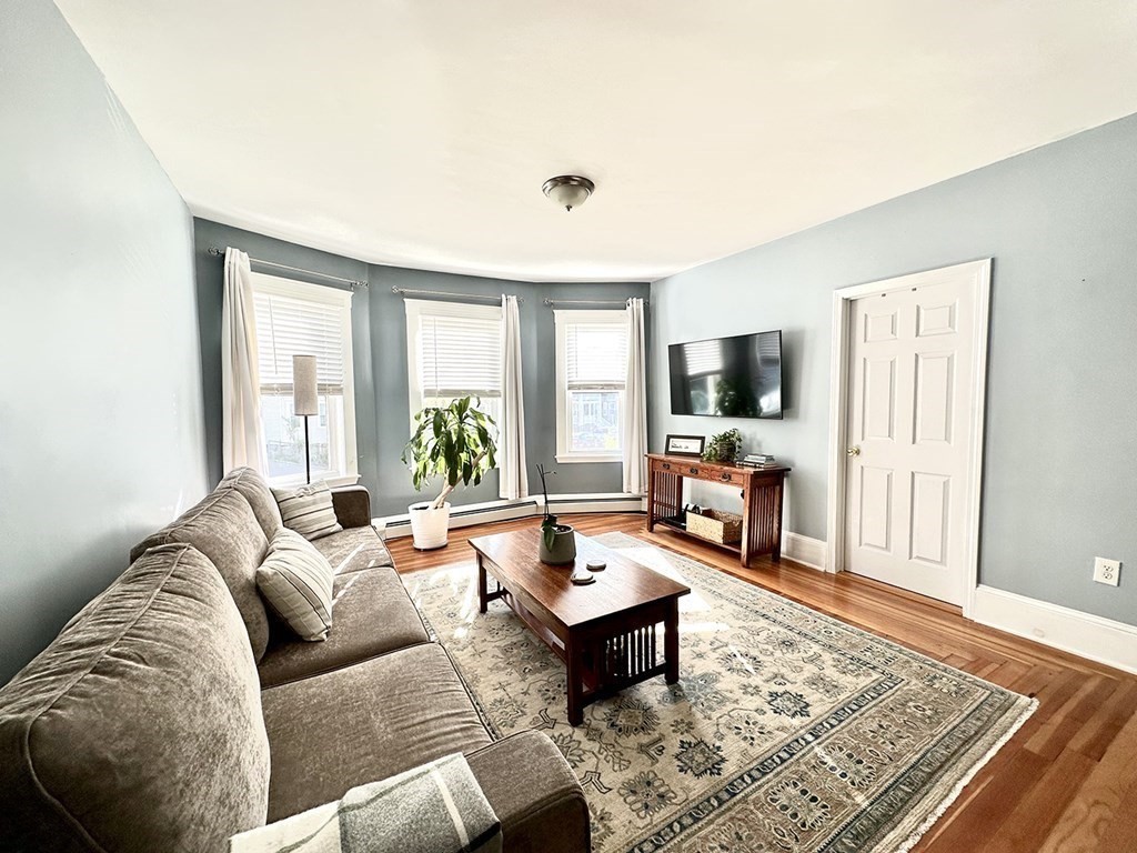 153 Rowe Street, Unit 1 Boston, MA 02131 - Photo 2 of 11 a living room with furniture and a flat screen tv