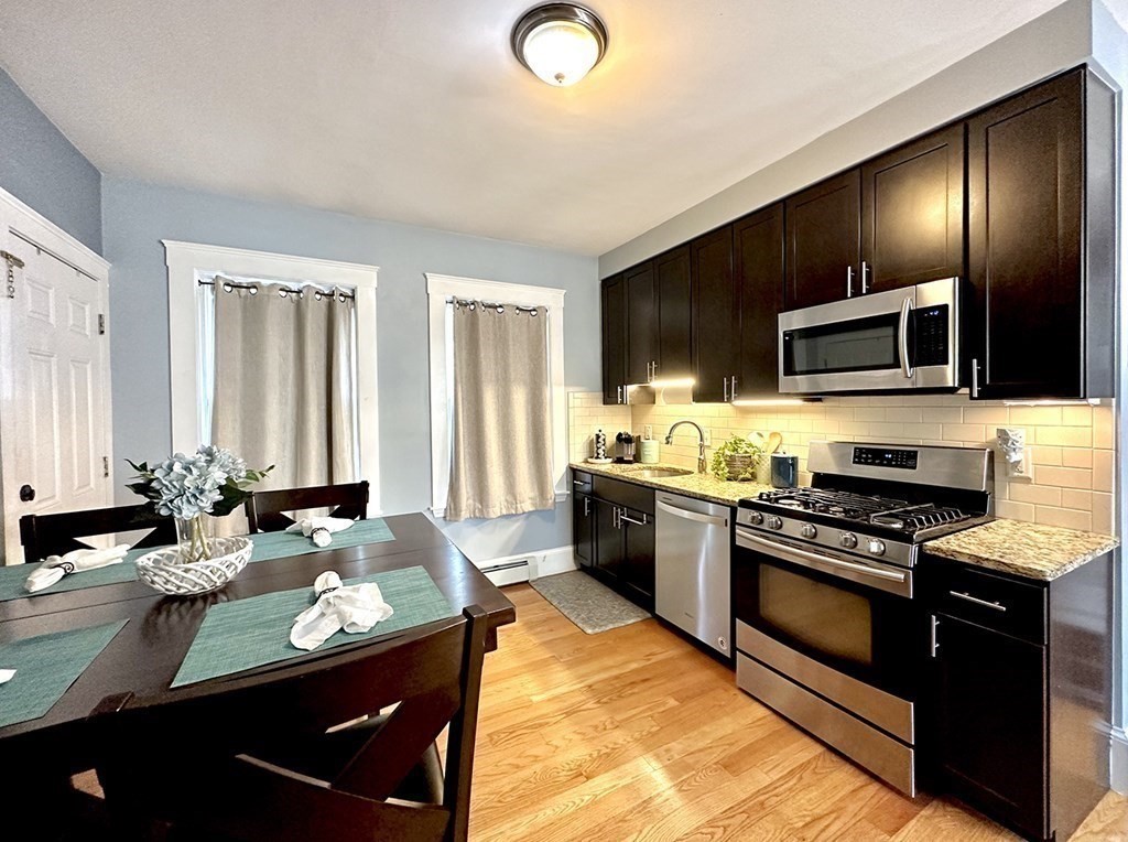 153 Rowe Street, Unit 1 Boston, MA 02131 - Photo 3 of 11 a kitchen with stainless steel appliances granite countertop a stove a sink and a microwave