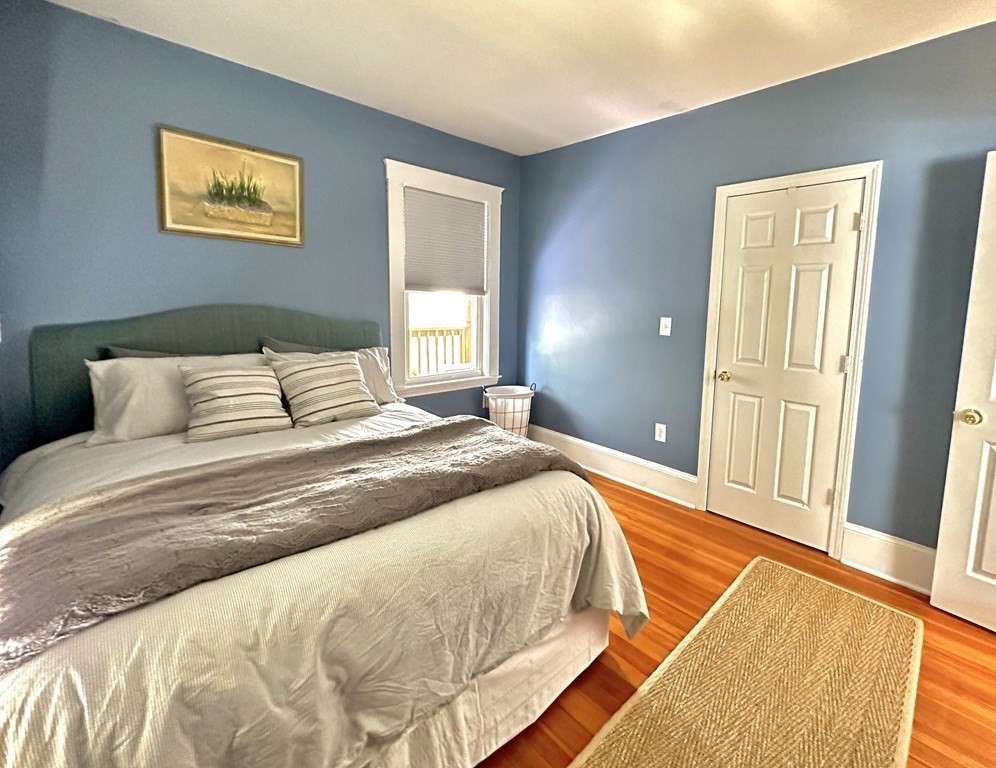 153 Rowe Street, Unit 1 Boston, MA 02131 - Photo 5 of 11 a bedroom with a bed and wooden floor