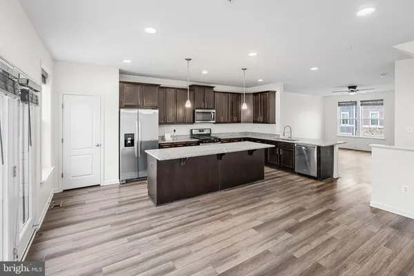 a large kitchen with stainless steel appliances granite countertop a large counter top a sink and a refrigerator