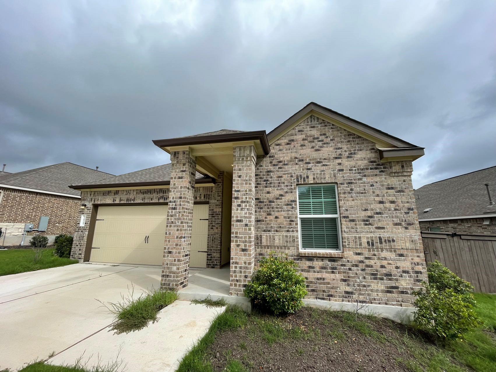 1625 Woolsey Way Leander, TX 78641 - Photo 2 of 17 The property features a brick exterior, an attached garage, and a covered entryway