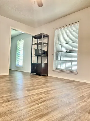a view of an empty room with window and wooden floor