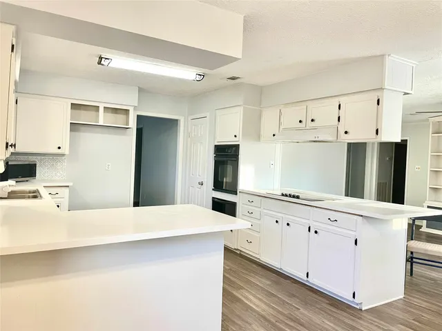 a kitchen with granite countertop white cabinets and refrigerator