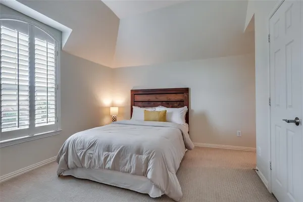 a bedroom with a bed and a lamp next to a window