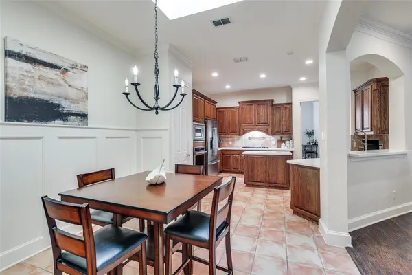 a kitchen with stainless steel appliances kitchen island granite countertop a table chairs and a refrigerator
