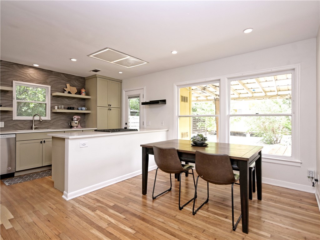 5707 Avenue F Austin, TX 78752 - Photo 6 of 17 a kitchen with stainless steel appliances granite countertop a kitchen island hardwood floor sink stove dining table and chairs