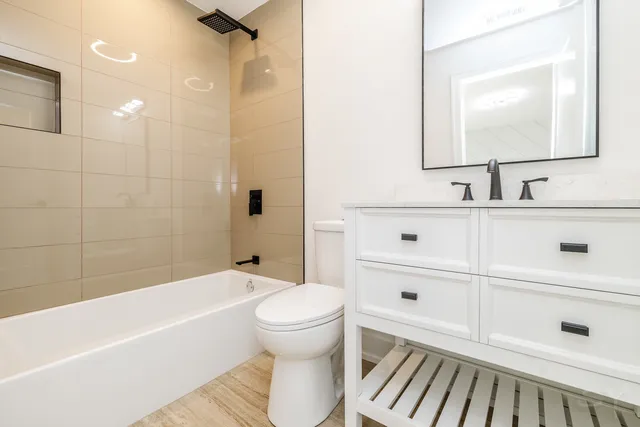a bathroom with a bathtub shower sink vanity and toilet