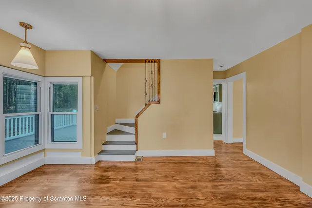 a view of empty room with wooden floor and window