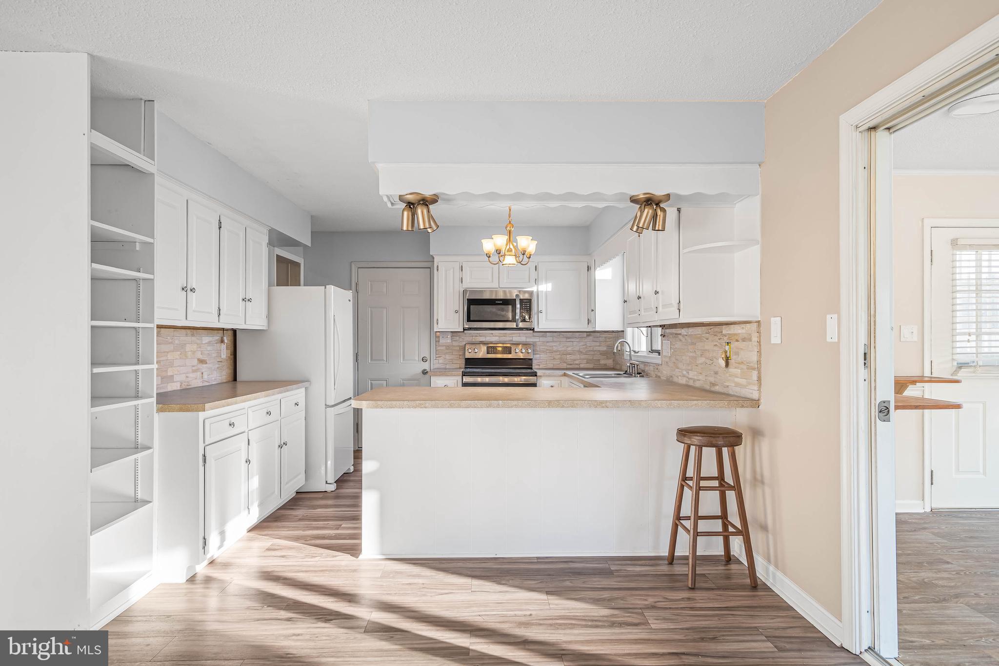 521 Harbor Road Ocean View, DE 19970 - Photo 14 of 32 a kitchen with white cabinets and stainless steel appliances