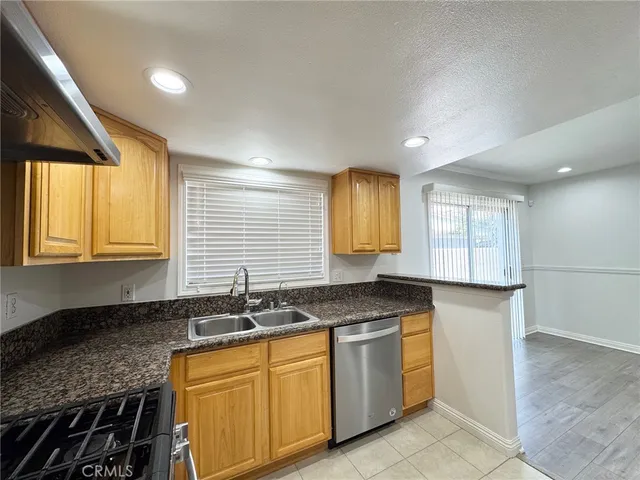 a kitchen with granite countertop stainless steel appliances a sink stove and cabinets