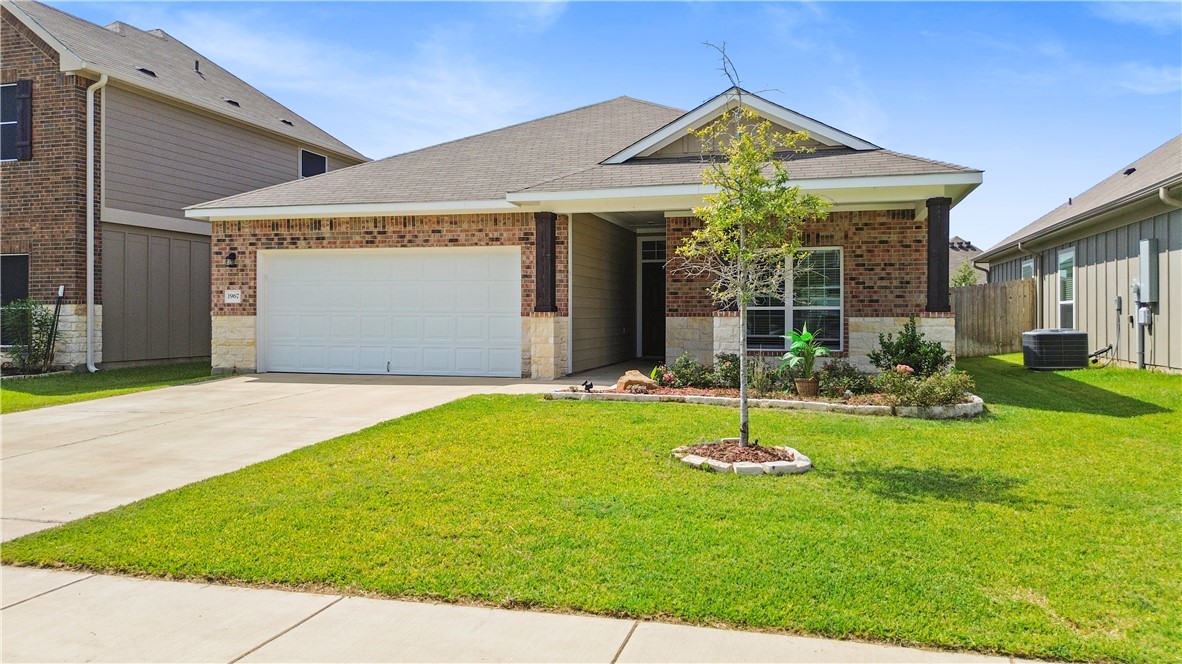 Single story home featuring driveway, a shingled roof, a garage, brick siding, and stone siding