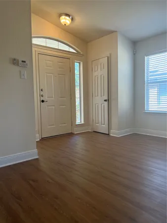 an empty room with wooden floor and windows