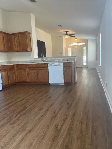 a kitchen with stainless steel appliances wooden floors wooden cabinets and entryway