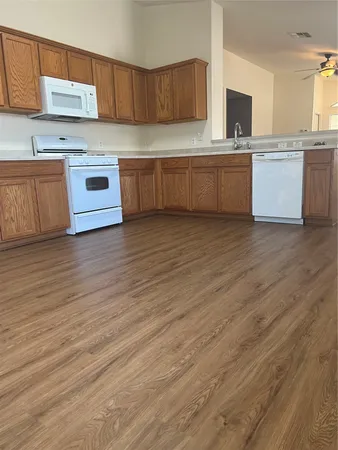 a large kitchen with granite countertop a stove top oven a sink a counter space and cabinets