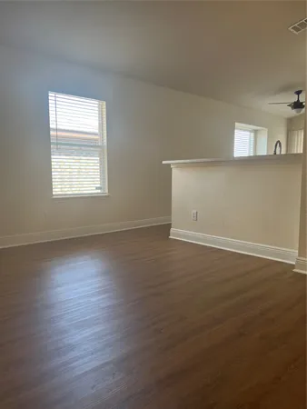 an empty room with wooden floor and windows