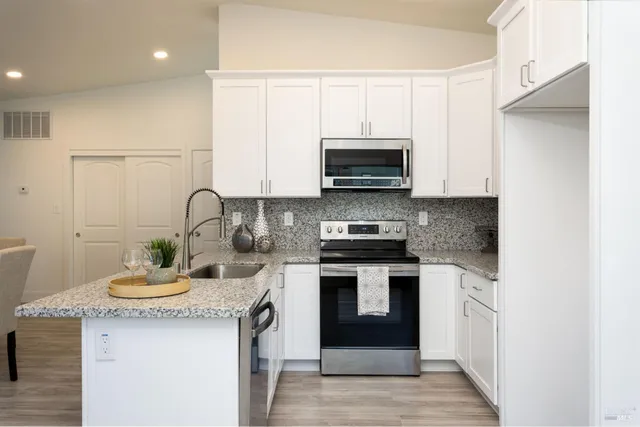 a kitchen with stainless steel appliances granite countertop a stove a sink and a microwave