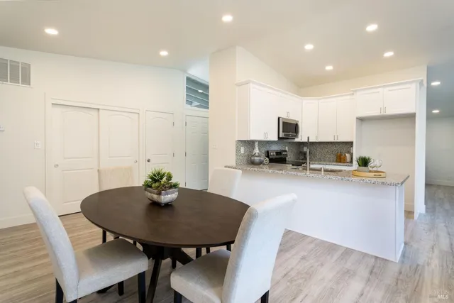 a kitchen with stainless steel appliances a dining table chairs and a refrigerator
