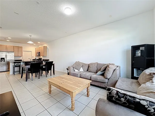 a living room with furniture a table and kitchen view