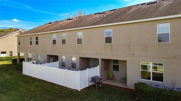 a view of a white house with a big yard and potted plants