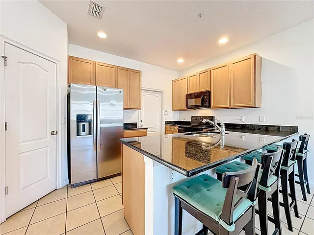 a kitchen with stainless steel appliances granite countertop a refrigerator a stove a sink a microwave and island