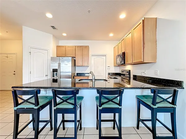 a kitchen with stainless steel appliances a table chairs refrigerator and wooden cabinets