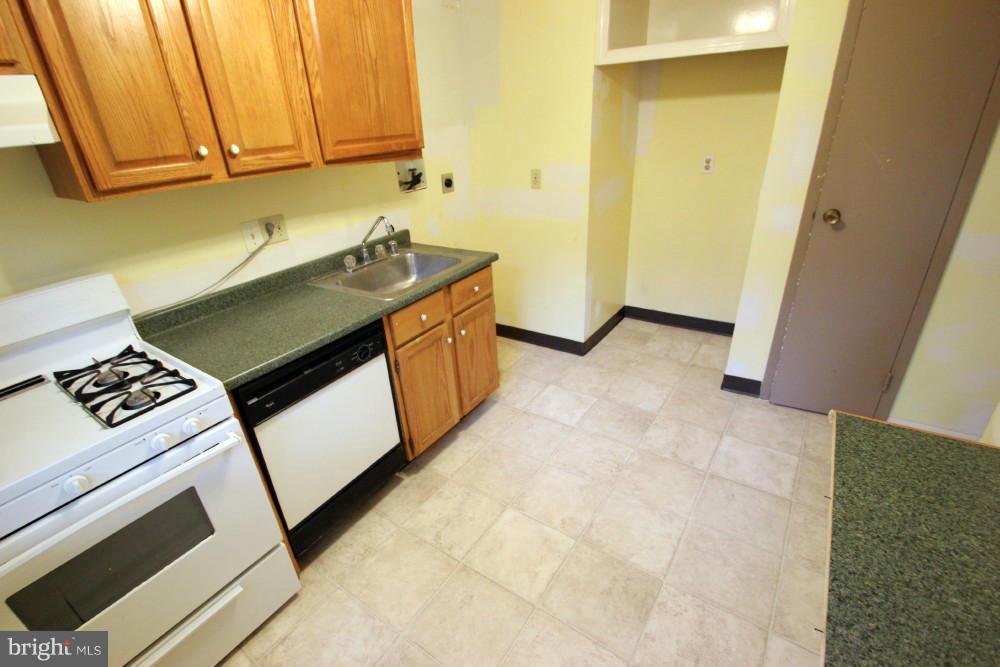 3934 Bel Pre Road, Unit 1 Silver Spring, MD 20906 - Photo 6 of 12 a kitchen with granite countertop a sink a stove a washer and dryer