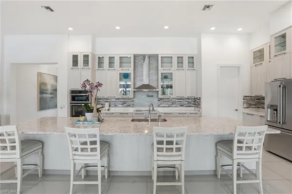 a kitchen with stainless steel appliances kitchen island granite countertop a dining table chairs and sink