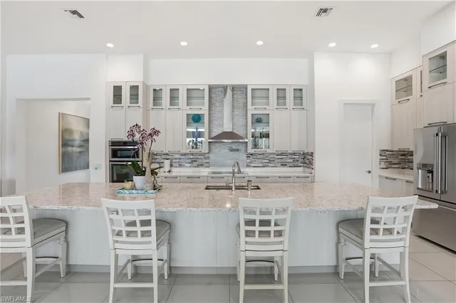 a kitchen with stainless steel appliances kitchen island granite countertop a dining table chairs and sink