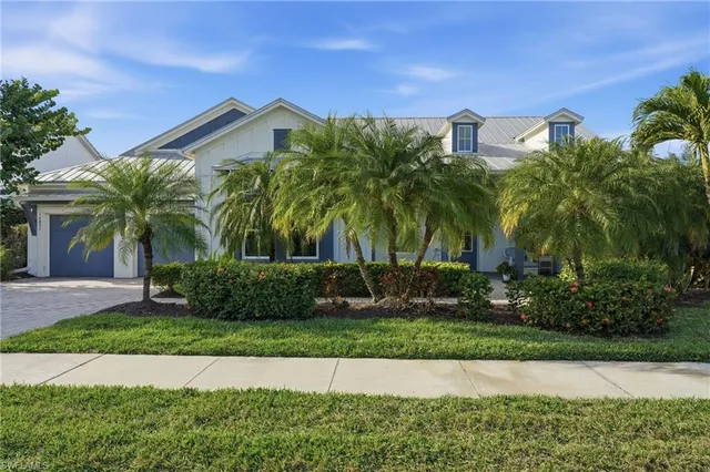 a front view of a house with a yard and palm trees