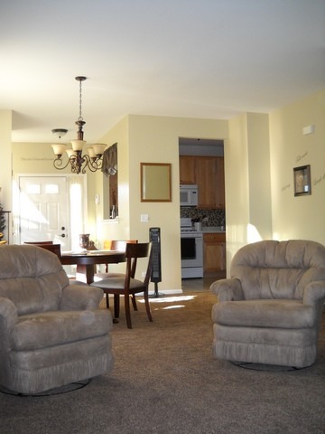 3016 Falling Waters Lane, Unit 3016 Lindenhurst, IL 60046 - Photo 9 of 21 a living room with furniture a dining table and a chandelier