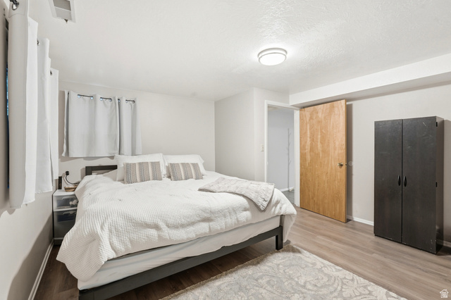 270 East 700 North Logan, UT 84321 - Photo 27 of 42 Bedroom featuring wood-finish flooring, light gray wall paint, and a wood-panel door