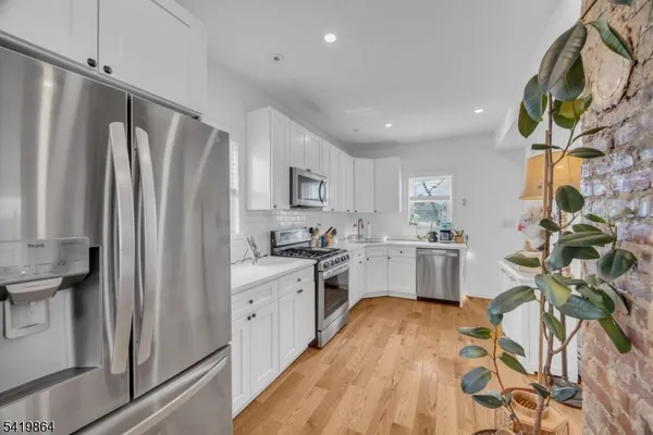 a kitchen with stainless steel appliances a refrigerator sink and white cabinets