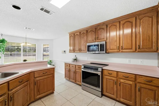 a kitchen with granite countertop wooden cabinets stainless steel appliances and a window