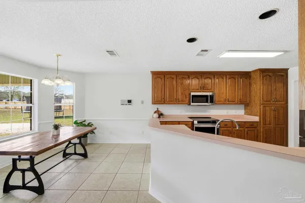 a large white kitchen with a stove a sink a microwave and dining table