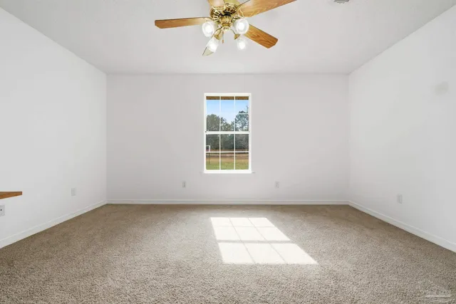 an empty room with a window and a ceiling fan