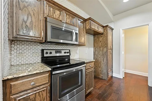a kitchen with granite countertop cabinets stainless steel appliances and wooden floor