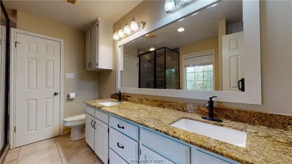 a bathroom with a granite countertop double vanity sink and a mirror