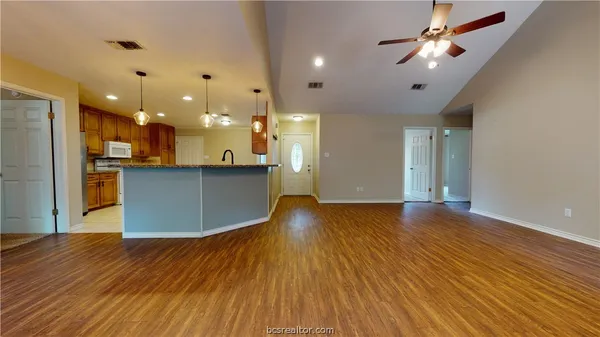 a view of a big room with wooden floor and a kitchen