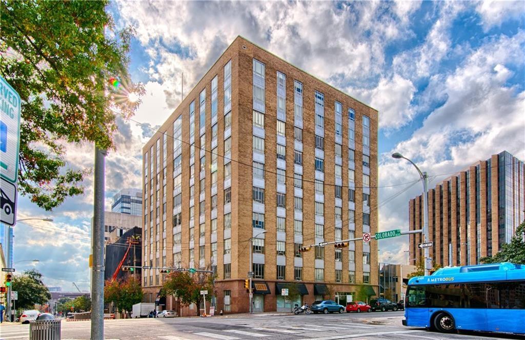 710 Colorado Street, Unit G9 Austin, TX 78701 - Photo 18 of 25 A prominent brick high-rise building anchors a lively urban intersection, embodying metropolitan living.