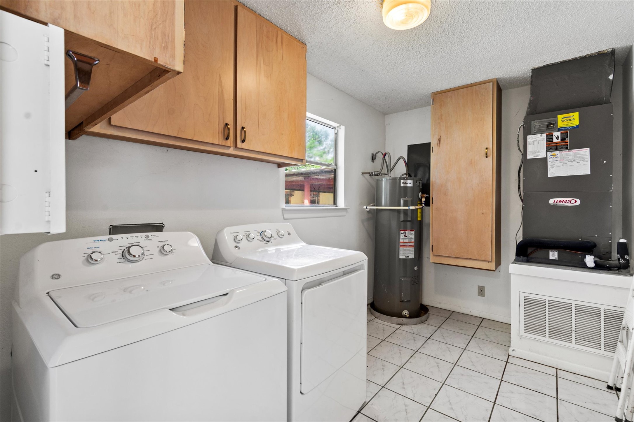 6 El Sol Road Wimberley, TX 78676 - Photo 12 of 20 Functional laundry room equipped with upper cabinetry, a window, and durable tiled flooring.