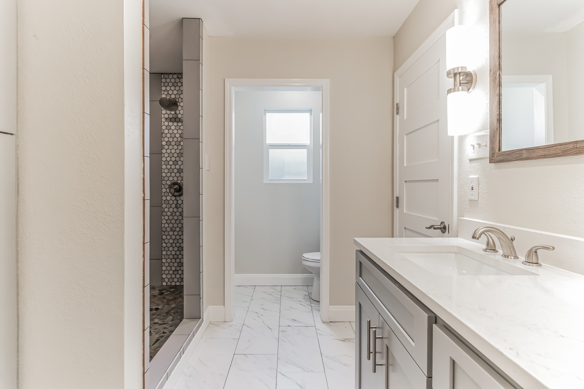 11406 Ruffed Grouse Drive Austin, TX 78758 - Photo 12 of 22 Gleaming stone counters pair with marble-patterned tile flooring in this renovated bathroom.