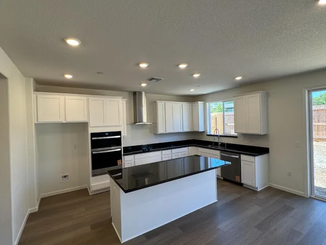 a kitchen with stainless steel appliances granite countertop a sink and a refrigerator