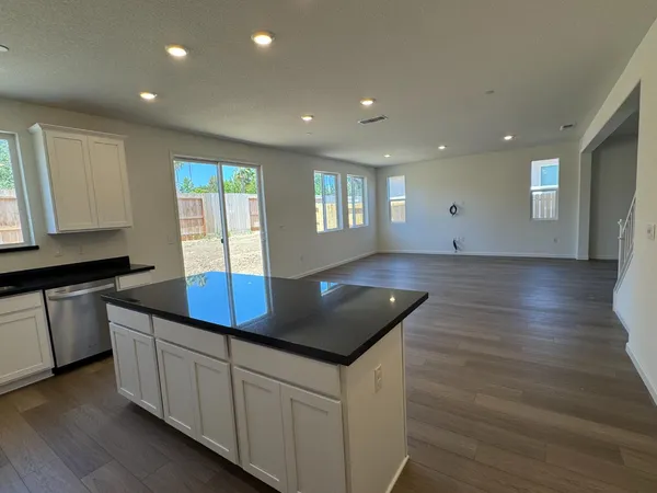 a kitchen with stainless steel appliances granite countertop a sink a stove and a wooden floors