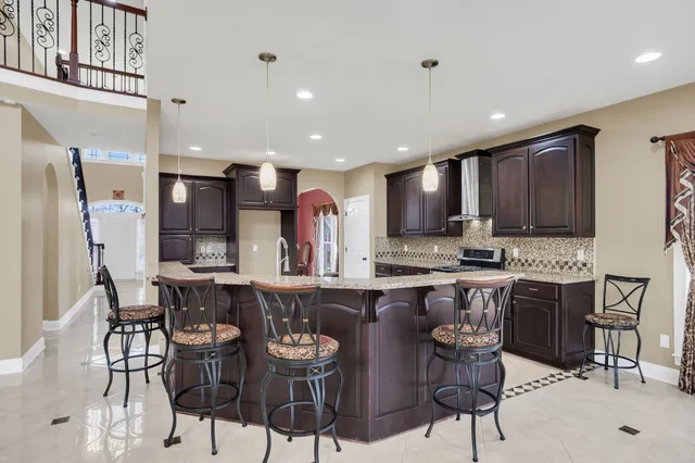 a kitchen with stainless steel appliances kitchen island granite countertop a dining table chairs sink and cabinets