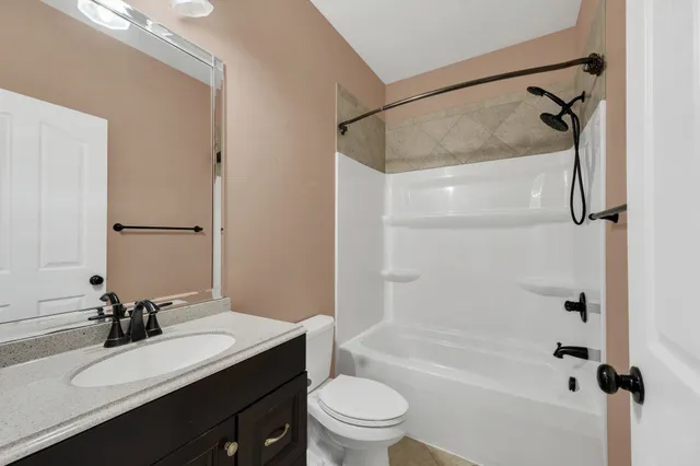 a bathroom with a bathtub shower sink vanity mirror and toilet