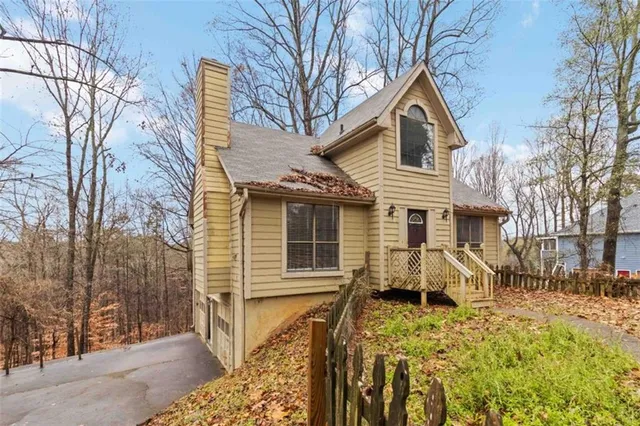 a view of a house with a yard chairs and wooden fence