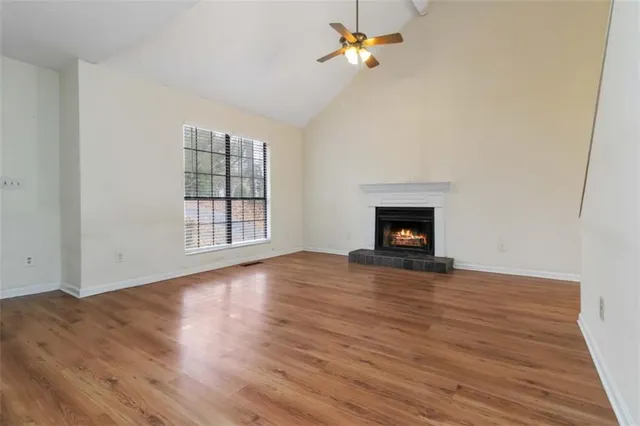 an empty room with wooden floor fireplace and window