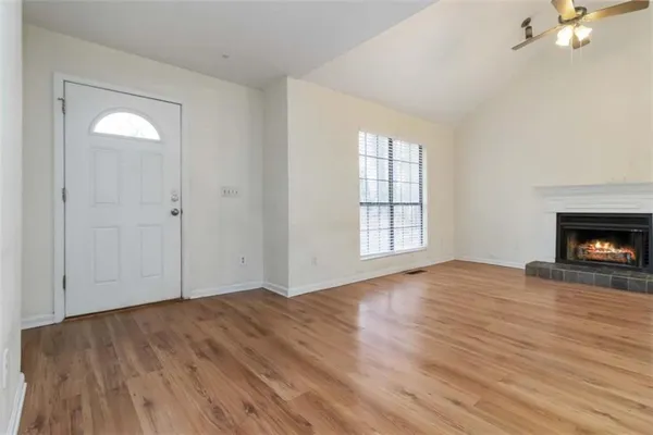 an empty room with wooden floor fireplace and windows