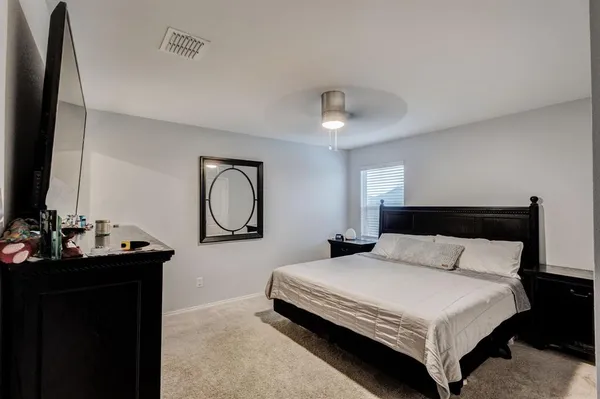 a bedroom with a bed and a flat tv screen on a dresser