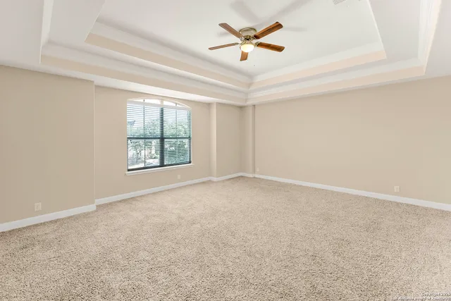 an empty room with windows and ceiling fan